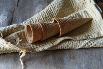 Порожні вафельні шишки для морозива на тканині на сірому дерев'яному столі — стокове фото