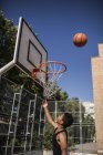 Teenager zielt Basketball in Korb auf Platz im Freien — Stockfoto