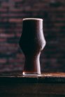 Cerveja Stout frio em vidro na mesa de madeira no fundo escuro — Fotografia de Stock