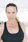 Selbstbewusste Frau in Sportbekleidung steht im Fitnessstudio und blickt in die Kamera — Stockfoto