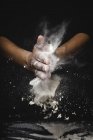 Human hands shaking off flour and pieces of dough on black background — Stock Photo
