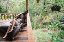 Молода жінка лежить на терасі в тропічному лісі і дивиться в сторону — стокове фото