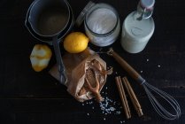 Arrangement rustique de riz, lait, épices et citrons sur table en bois noir avec ustensile — Photo de stock