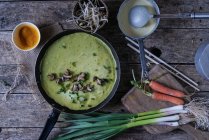 Sartén con crepe verde de Banh Xeo con verduras frescas en proceso de cocción - foto de stock