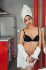 Sensual jovem mulher em lingerie e toalha na cabeça de pé em casa e olhando para a câmera — Fotografia de Stock