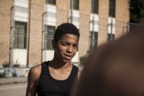 Мальчик-афро прищуривается на улице перед зданием — стоковое фото