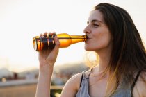 Felice giovane donna che beve birra dalla bottiglia all'aperto — Foto stock
