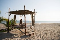 Mulher sentada em uma pequena cabana de madeira e olhando para o oceano na praia na Tailândia — Fotografia de Stock