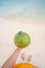 Crop man che tiene cocco verde sulla spiaggia — Foto stock