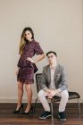 Stylish young couple in fashionable clothes looking at camera in front of beige wall — Stock Photo