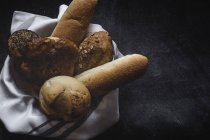 Frisch gebackene Brotlaibe auf Stoff auf schwarzem Hintergrund — Stockfoto