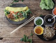 Vietnamese savory fried pancake with vegetables and ingredients on wooden table — Stock Photo