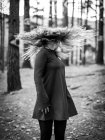 Черно-белый перевернутый снимок неузнаваемой женщины, стоящей в светлых лесах и трясущейся шерсти — стоковое фото