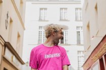 Стильный мужчина с светлыми волосами и розовой футболкой, кричащий на улице — стоковое фото