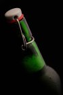 Primer plano de botella de cerveza sobre fondo oscuro - foto de stock