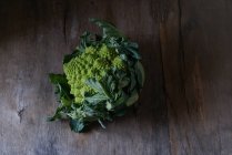 Mani in mano con broccoli romanesco freschi — Foto stock