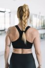 Back view of female athlete in black sportswear standing in gym — Stock Photo