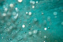 Amazing background of sandy ocean floor and stunning turquoise wave with air bubbles rising up — Stock Photo