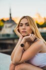 Blonde young woman in casual outfit looking at camera while sitting in city — Stock Photo