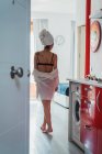 Mulher magra em lingerie e toalha no cabelo andando em casa — Fotografia de Stock