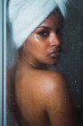Mujer seductora detrás de vidrio de ducha humeante mirando a la cámara - foto de stock