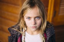 Retrato de chica rubia con ojos azules de pie fondo de madera - foto de stock