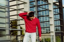 Привабливий молодий чоловік в червоному пуловері стоїть перед будівлею — стокове фото