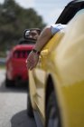 Male hand hanging from window of yellow shiny luxury car — Stock Photo