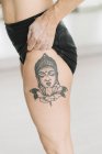 Close-up of female athlete showing Buddha tattoo on leg — Stock Photo