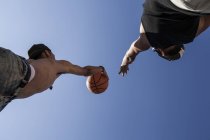 Giovani fratelli che giocano a basket contro il cielo blu — Foto stock