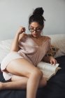 Sinnliche brünette Frau mit Buch chillen auf dem Bett — Stockfoto