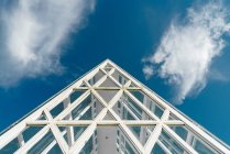Vue de dessous de la construction en verre du toit en pente avec des poutres blanches sous le ciel bleu, Phoenix Park, Chine — Photo de stock