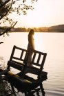 Мечтательная женщина, стоящая на затонувшем пирсе при солнечном свете — стоковое фото