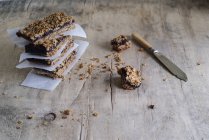 Barrette di granola impilate fatte in casa su carta da forno su superficie di legno — Foto stock