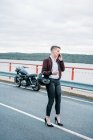 Donna attraente che parla con lo smartphone accanto alla sua moto retrò — Foto stock