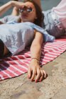 Розслаблена жінка в сонцезахисних окулярах лежить на ногах на друзів на набережній — стокове фото