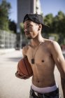 Young afro boy holding basketball on court of neighborhood — Stock Photo