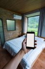 Cortar mão segurando smartphone em um quarto elegante com vista para as montanhas chinesas — Fotografia de Stock