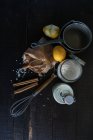 Сельский укладка риса, молока, специй и лимонов на черном деревянном столе с посудой — стоковое фото