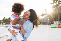 Glückliche ethnische Frau mit Kind am Strand — Stockfoto