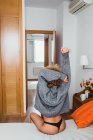 Ethnische Frau in schwarzem Höschen und grauem Pullover, die sich zu Hause auf dem Bett dehnt — Stockfoto