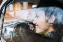 Крупным планом улыбающейся молодой женщины за рулем автомобиля — стоковое фото