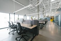 Interior tiro de novo escritório de espaço aberto com móveis coloridos no local de trabalho e luz das janelas — Fotografia de Stock