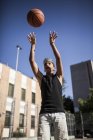 Молодий хлопчик в шапці грає в баскетбол на дворі на відкритому повітрі — стокове фото
