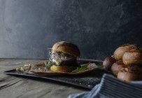 Tasty hamburger with lentil and purple carrot on tray with parchment — Stock Photo