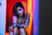 Чуттєва молода жінка з татуюваннями дивиться на камеру, позуючи в туалеті під час вечірки — стокове фото