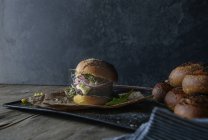 Смачний гамбургер з сочевицею та фіолетовою морквою на підносі з пергаментом — стокове фото