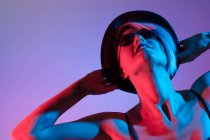 Attrayant femme avec chapeau tirer en studio avec des lumières bleues et rouges — Photo de stock