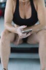 Athlète féminine assise sur un banc et utilisant une application de fitness sur smartphone — Photo de stock