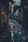 View of narrow dirty and grungy street flooded with water and trash floating on top — Stock Photo